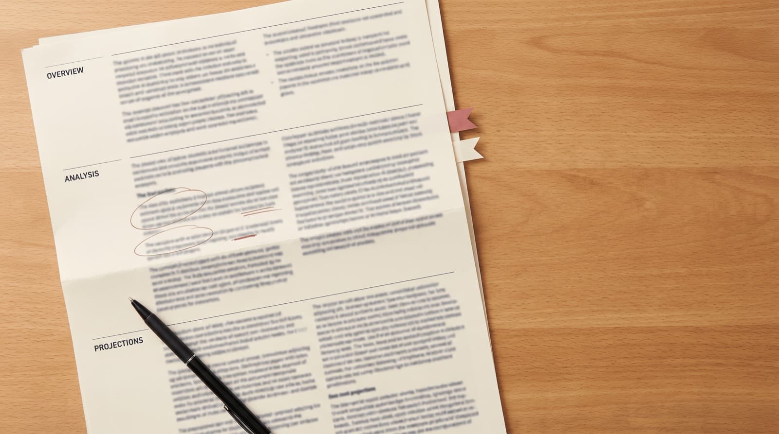 A financial statement on a wooden desk with one line circled in red, a flag tab on the page edge, and a pen resting across it
